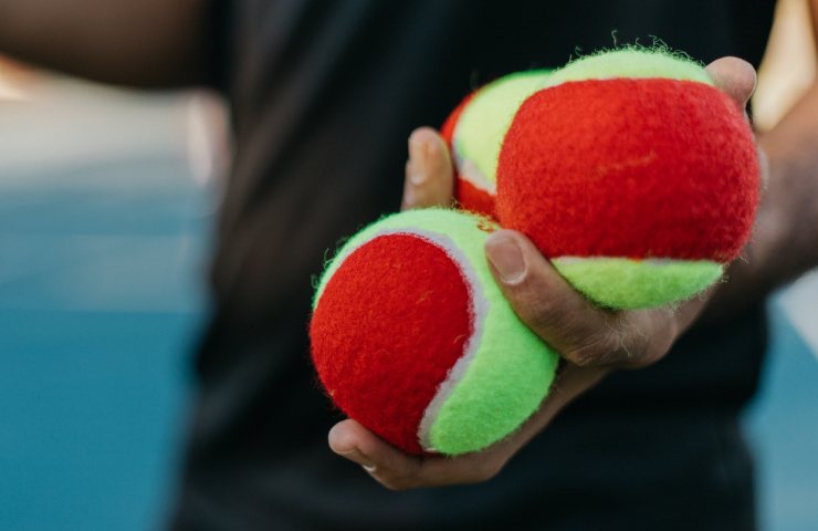 Tre palline da tennis in mano a un uomo
